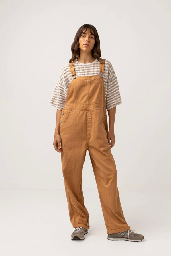 A durable cotton drill jumpsuit in a casual, relaxed fit, the Brodie Jumpsuit in soft Ecru is an easy throw on made for everyday wear, featuring adjustable buckle straps, button side opening, contrast stitch details and side entry pockets.