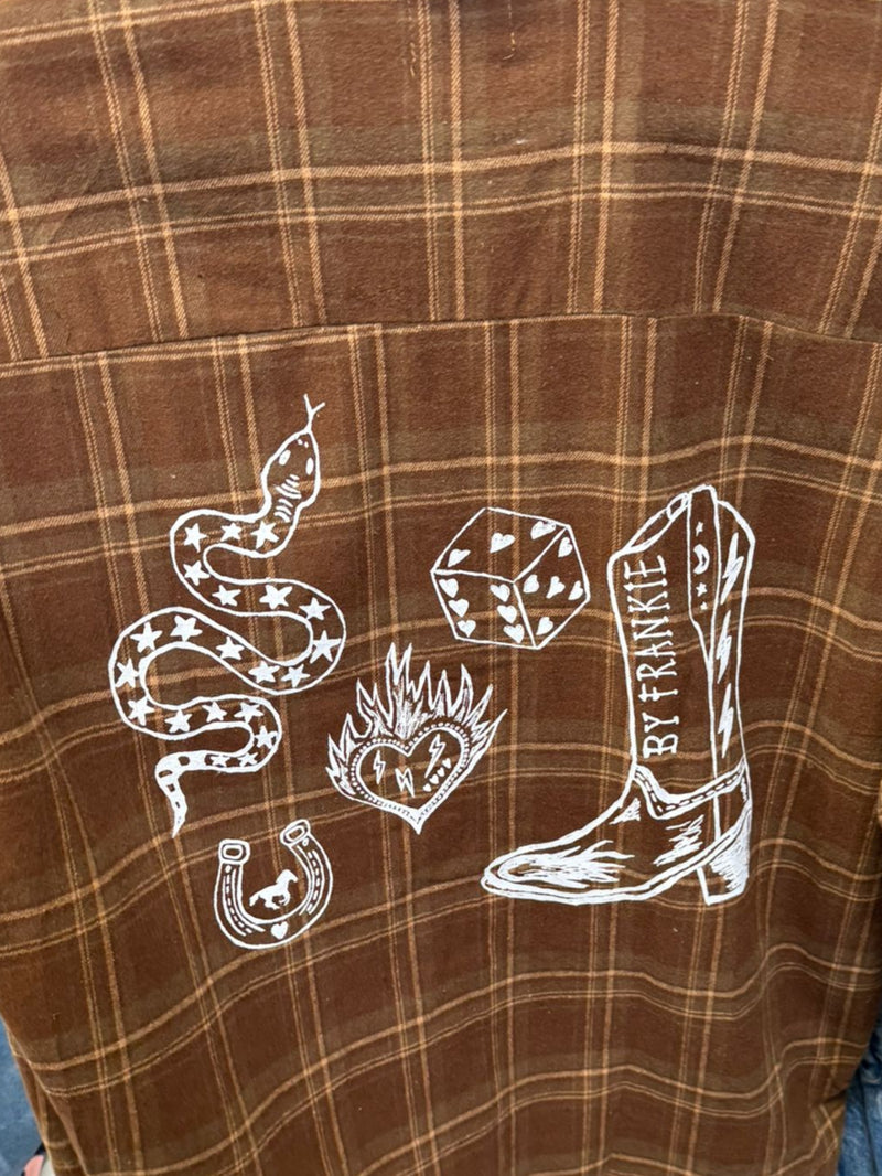 Brown plaid shirt with white graphic design on a clothing rack.